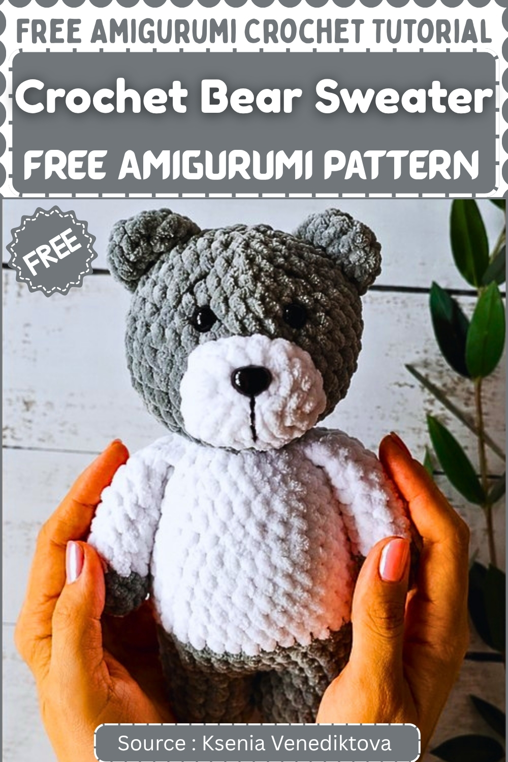 Two hands holding up a completed gray and white crochet bear amigurumi wearing a white sweater body with a gray head and ears displayed in front of green foliage
