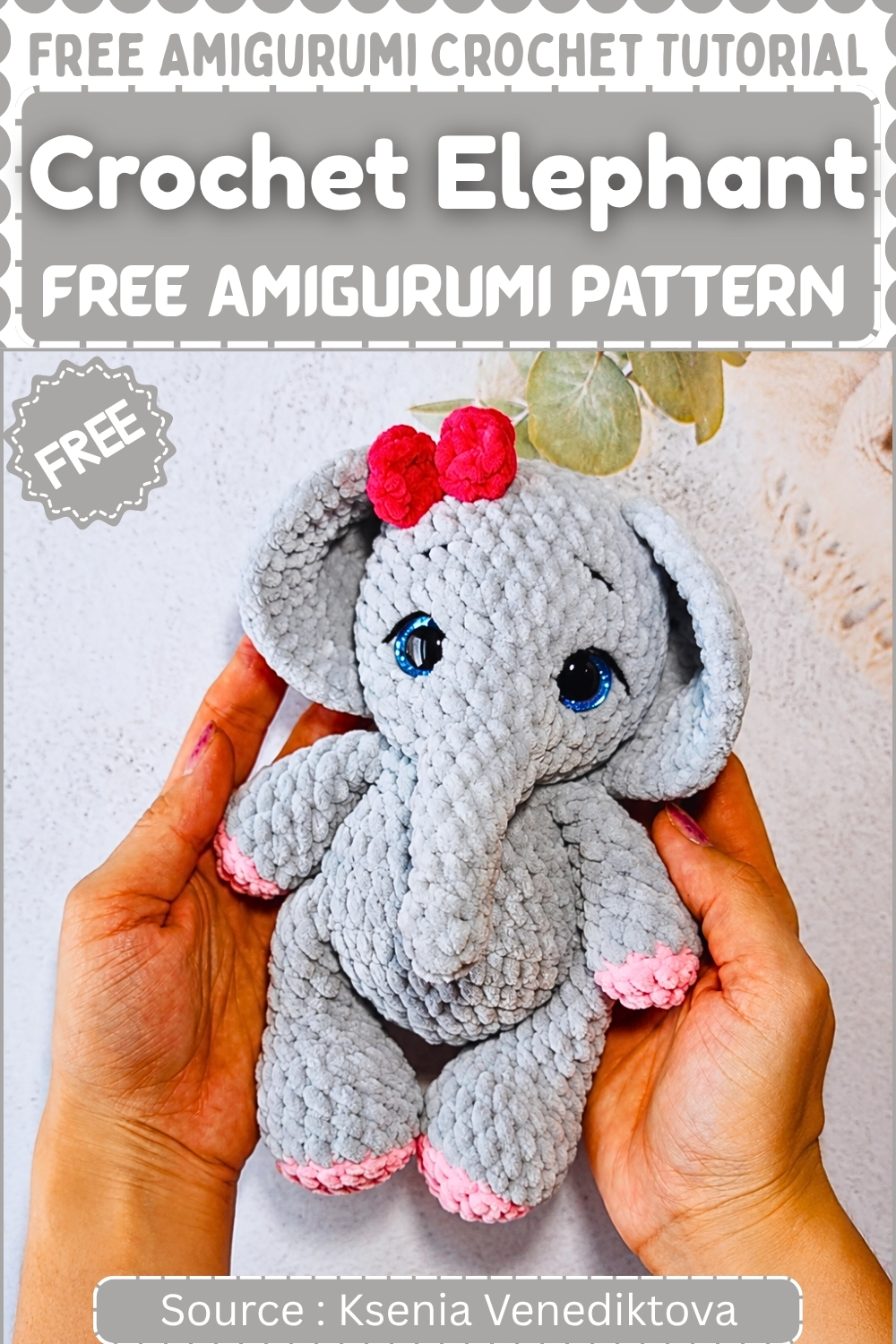 Completed gray crochet elephant amigurumi with pink accents blue safety eyes and a red bow held up in two hands against a light background