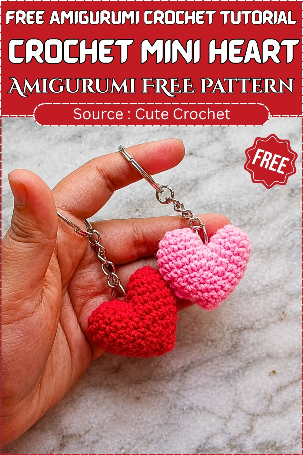Hand displaying two finished crochet mini heart keychains in red and pink attached to silver chains against a marble background