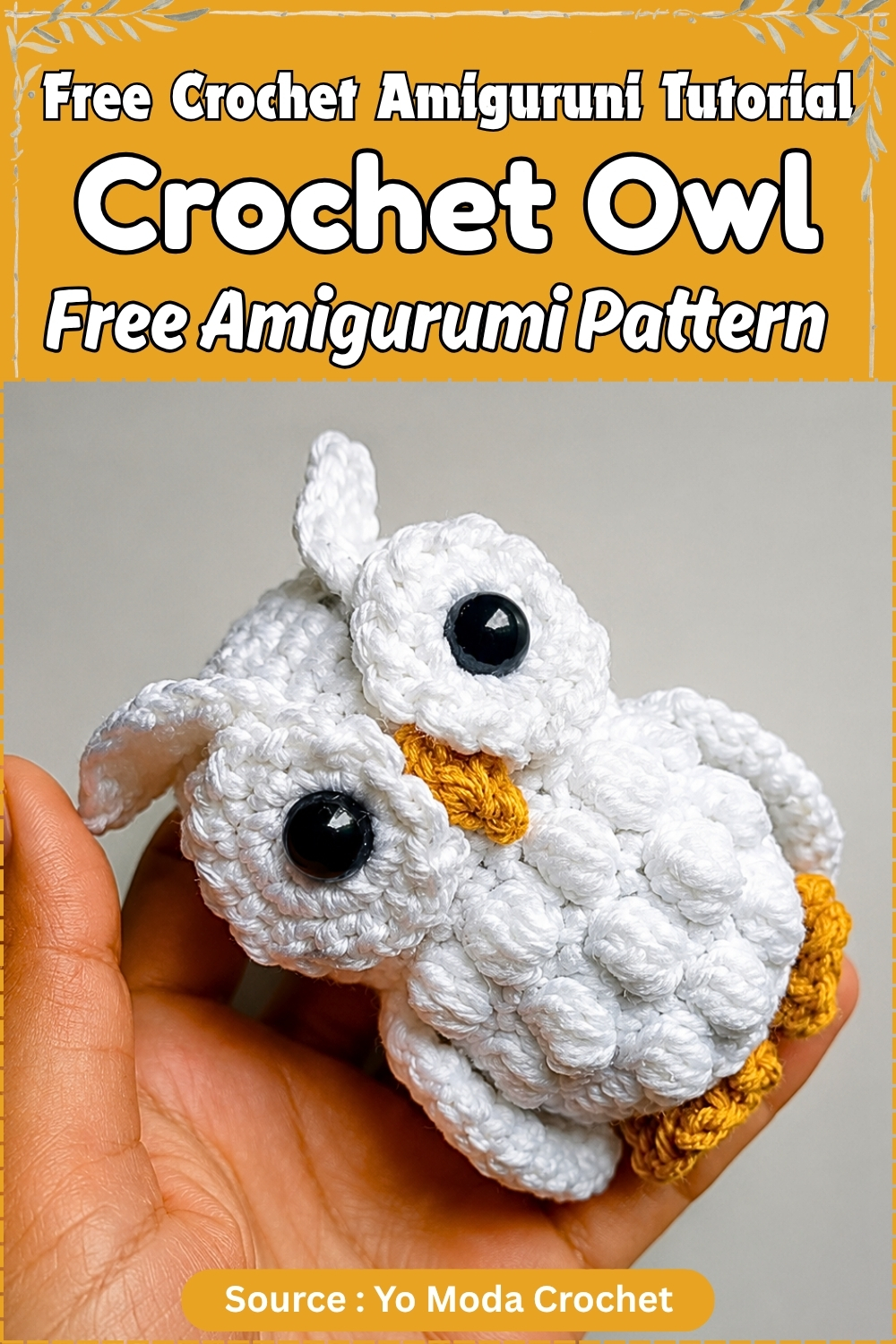 Hand holding a finished crochet owl amigurumi in white with mustard yellow feet and beak and oversized black safety eyes against a neutral background