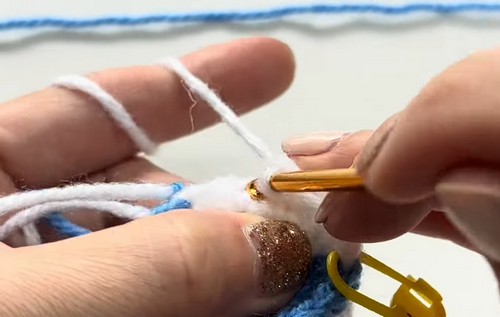 Hands switching from blue to white yarn using a yellow crochet hook while crocheting the belly section of a whale shark amigurumi.