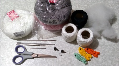 Hands joining the cream-colored belly piece to the gray body of a crochet hammerhead shark amigurumi.