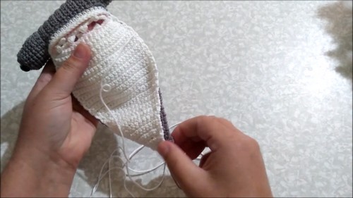 Hands joining the cream-colored belly piece to the gray body of a crochet hammerhead shark amigurumi