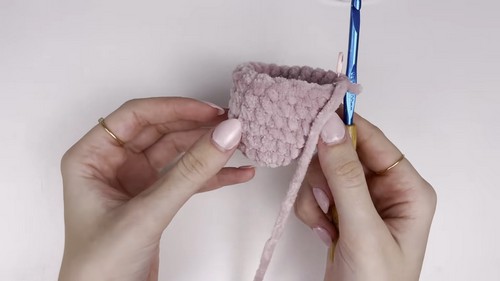 Hands holding a small open pink chenille cup shape showing the inner mouth piece of a bass amigurumi before it is joined to the body.